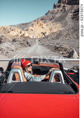 Woman traveling by cabriolet car on the desert road 62978974