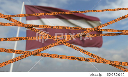 Caution biohazard tape with flag of Latvia as a background. Latvian restricted border crossing or quarantine. Conceptual 3D rendering 62982042