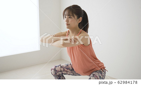筋肉トレーニングをする若い女性　スクワット 62984178