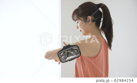 ウェアラブルデバイスを操作する若い女性 62984254