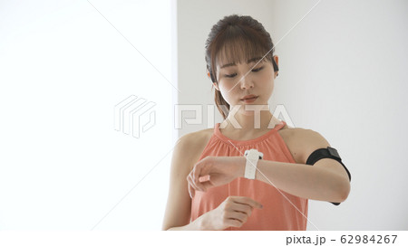 ウェアラブルデバイスを操作する若い女性 62984267