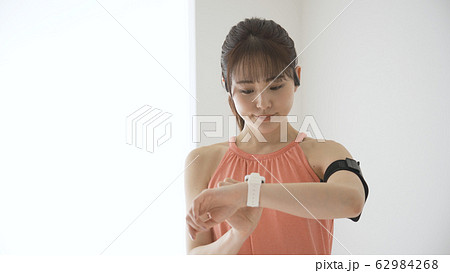 ウェアラブルデバイスを操作する若い女性 62984268