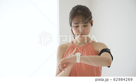 ウェアラブルデバイスを操作する若い女性 62984269