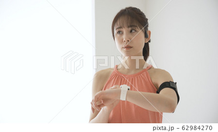 ウェアラブルデバイスを操作する若い女性 62984270