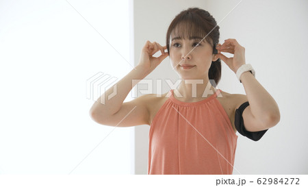 ウェアラブルデバイスを操作する若い女性 62984272