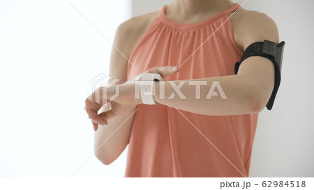 ウェアラブルデバイスを操作する若い女性 62984518