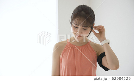 ウェアラブルデバイスを操作する若い女性 62984529