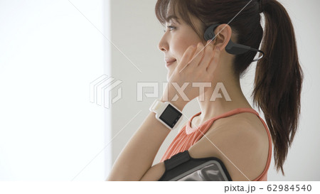 ウェアラブルデバイスを操作する若い女性 62984540