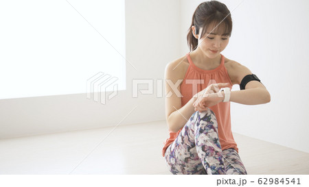 ウェアラブルデバイスを操作する若い女性 62984541