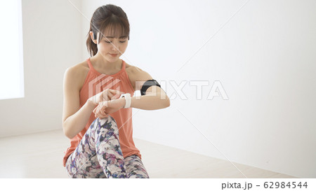 ウェアラブルデバイスを操作する若い女性 62984544