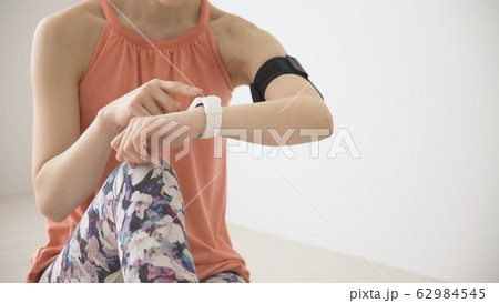 ウェアラブルデバイスを操作する若い女性 62984545
