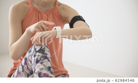 ウェアラブルデバイスを操作する若い女性 62984546