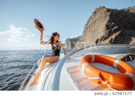 Woman sailing on the yacht near the rocky coast 62987277