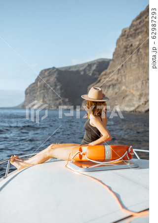Woman sailing on the yacht near the rocky coast Woman sailing on the yacht near the rocky coast 62987293