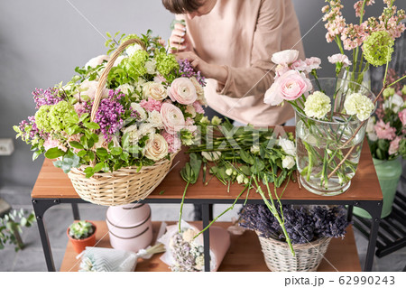 Floral shop concept . Florist woman creates flower arrangement in a wicker basket. Beautiful bouquet of mixed flowers. Handsome fresh bunch. Flowers delivery. 62990243
