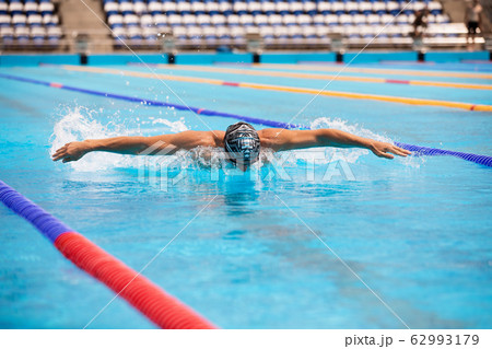 Athletic man swimming in butterfly style in the swimming pool with clear blue water. Athletic man swimming in butterfly style in the swimming pool with clear blue water. 62993179