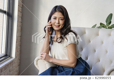 ソファに座って電話する女性 ソファに座って電話する女性 62996055