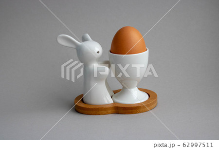 Easter bunny rabbit with brown egg on gray background. Easter holiday concept 62997511