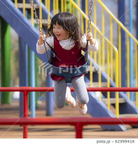 ブランコで遊ぶ3歳の女の子 遊具で遊ぶ3歳の女の子 公園で遊ぶ3歳の女の子の写真素材