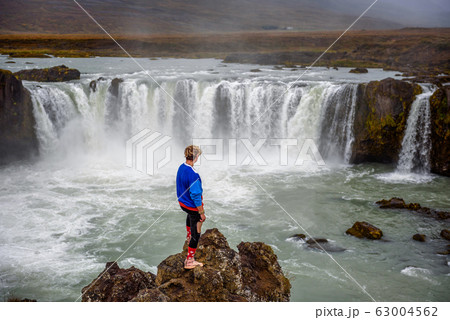 Hiker standing at the Godafoss waterfall in Iceland 63004562