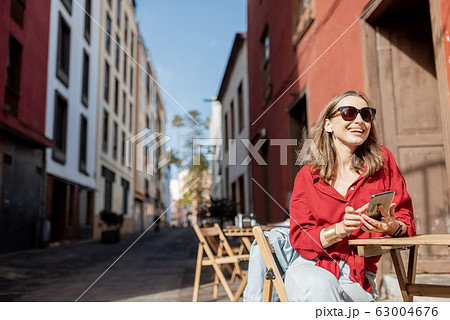 Woman with phone on the cafe terrace outdoors 63004676