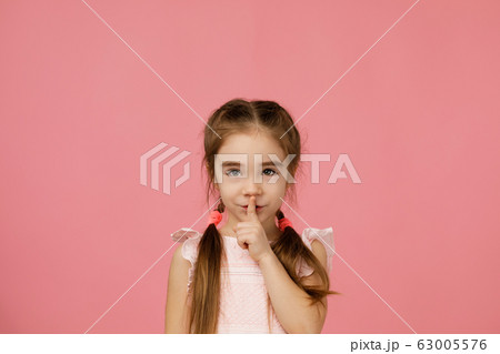 beautiful little girl asking to be quiet with finger on lips beautiful little girl asking to be quiet with finger on lips 63005576