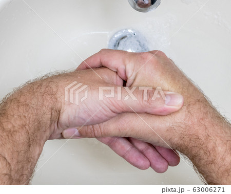 Man washing hands close-up from above 63006271