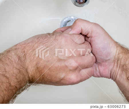Man washing hands close-up from above 63006273