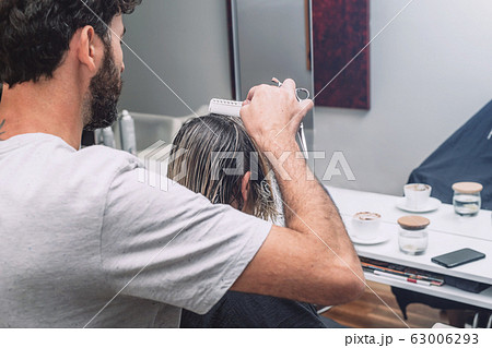 Master hairdresser cuts hair of blond woman in salon. Close up photo 63006293