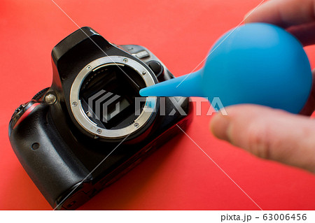 Photographer cleaning photocamera light sensor. Photographer cleaning photocamera light sensor. 63006456