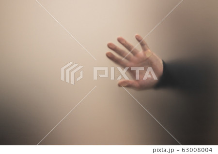 Blurred male hand behind gray matte glass wall 63008004