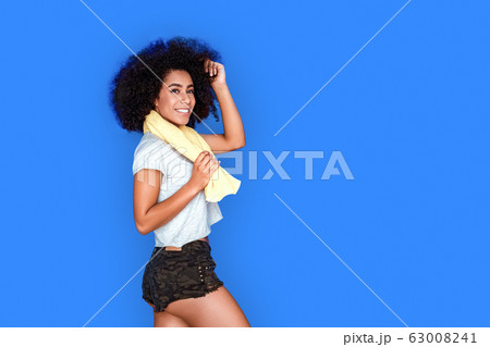 Freestyle. Mulatto girl walking isolated on blue with towel around neck smiling toothy 63008241