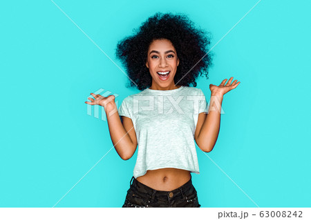 Freestyle. African american girl standing isolated on blue hands aside looking camera impressed Freestyle. African american girl standing isolated on blue hands aside looking camera impressed 63008242