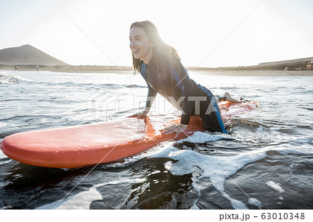 Woman surfing in the sea Woman surfing in the sea 63010348