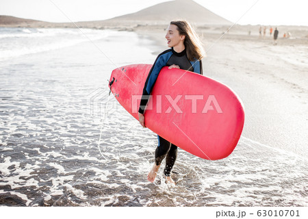 Young surfer with surfboard on the beach 63010701