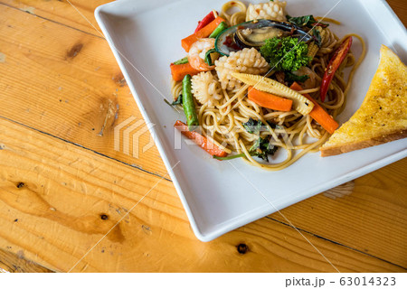 Seafood spaghetti, shrimp, squid, vegetables Asian cuisine is popular on white plates on wooden floors. Seafood spaghetti, shrimp, squid, vegetables Asian cuisine is popular on white plates on wooden floors. 63014323