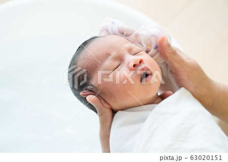 Mother is washing baby hair. Mom cleaning her baby hair. Mother is washing baby hair. Mom cleaning her baby hair. 63020151