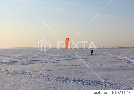 Man is engaged in snowkiting on a frozen 63021173