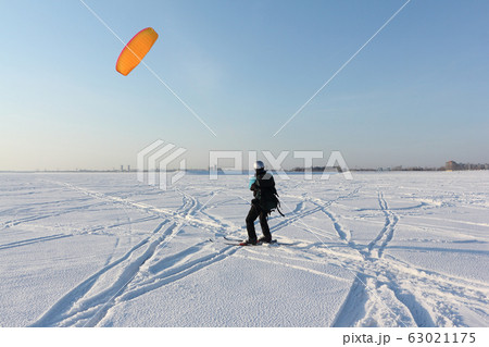 Man is engaged in snowkiting on a frozen Man is engaged in snowkiting on a frozen 63021175
