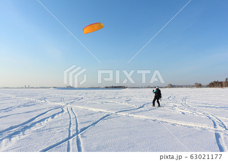 Man is engaged in snowkiting on a frozen Man is engaged in snowkiting on a frozen 63021177