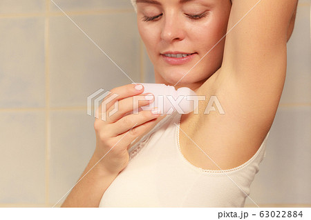 Woman applying stick deodorant in armpit 63022884