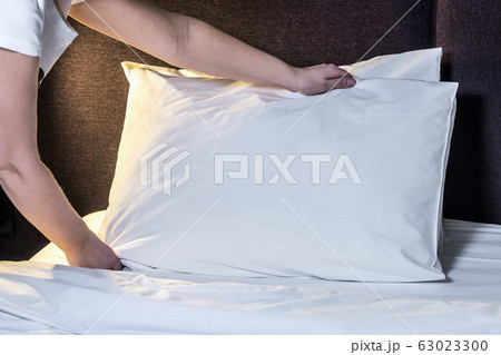 female hands corrected pillow on the bed 63023300