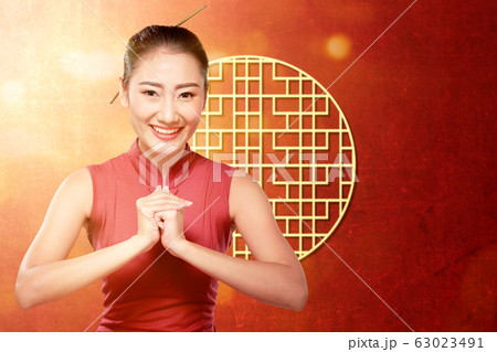 Asian Chinese woman in a cheongsam dress with congratulations gesture Asian Chinese woman in a cheongsam dress with congratulations gesture 63023491