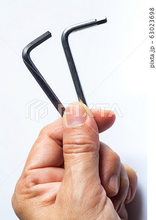 Woman's left using Black Hexagonal L Key Wrench and Metallic Hex Key on White Background, Close up and Macro shot, Hand mechanic tools concept Woman's left using Black Hexagonal L Key Wrench and Metallic Hex Key on White Background, Close up and Macro shot, Hand mechanic tools concept 63023698