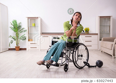 Young male invalid in wheel-chair suffering at home Young male invalid in wheel-chair suffering at home 63027443