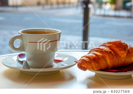 Cup of Coffee and a Croissant on a Table of a 63027569