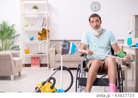 Young man in wheel-chair cleaning the house 63027725