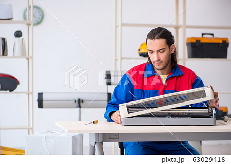 Young male contractor repairing air-conditioner at workshop 63029418