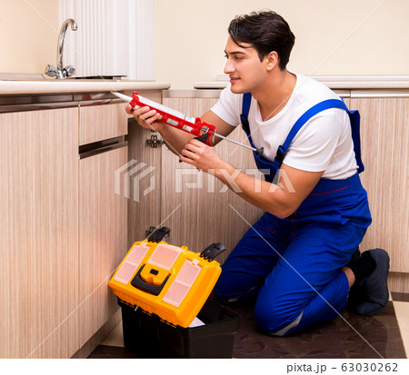 Young repairman working at the kitchen Young repairman working at the kitchen 63030262
