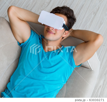 The young man wearing vr glasses relaxing on couch sofa The young man wearing vr glasses relaxing on couch sofa 63030271